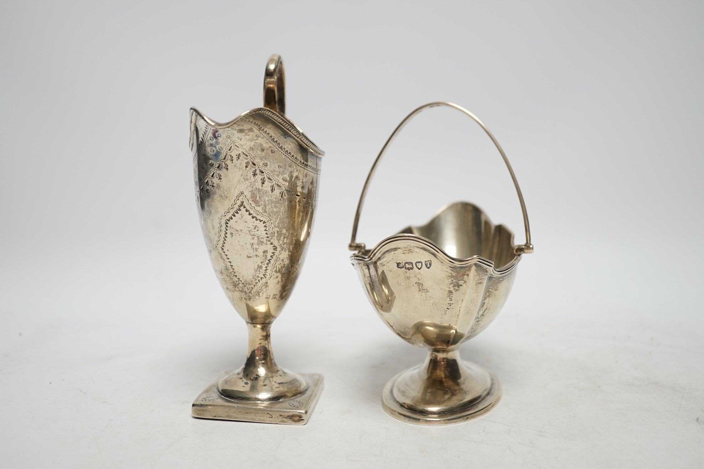 A late Victorian silver oval sugar basket, by Thomas Bradbury & Sons, London, 1894, height length 13.5cm (fair condition), together with a George III silver cream jug, marks rubbed, 8.5oz, (poor condition).